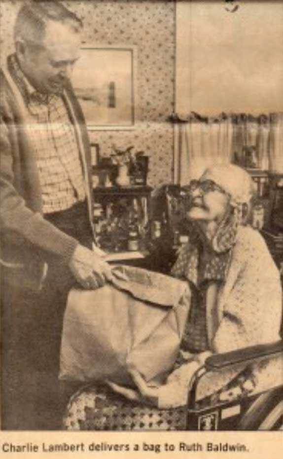 newspaper clipping of volunteer delivering food bag.
